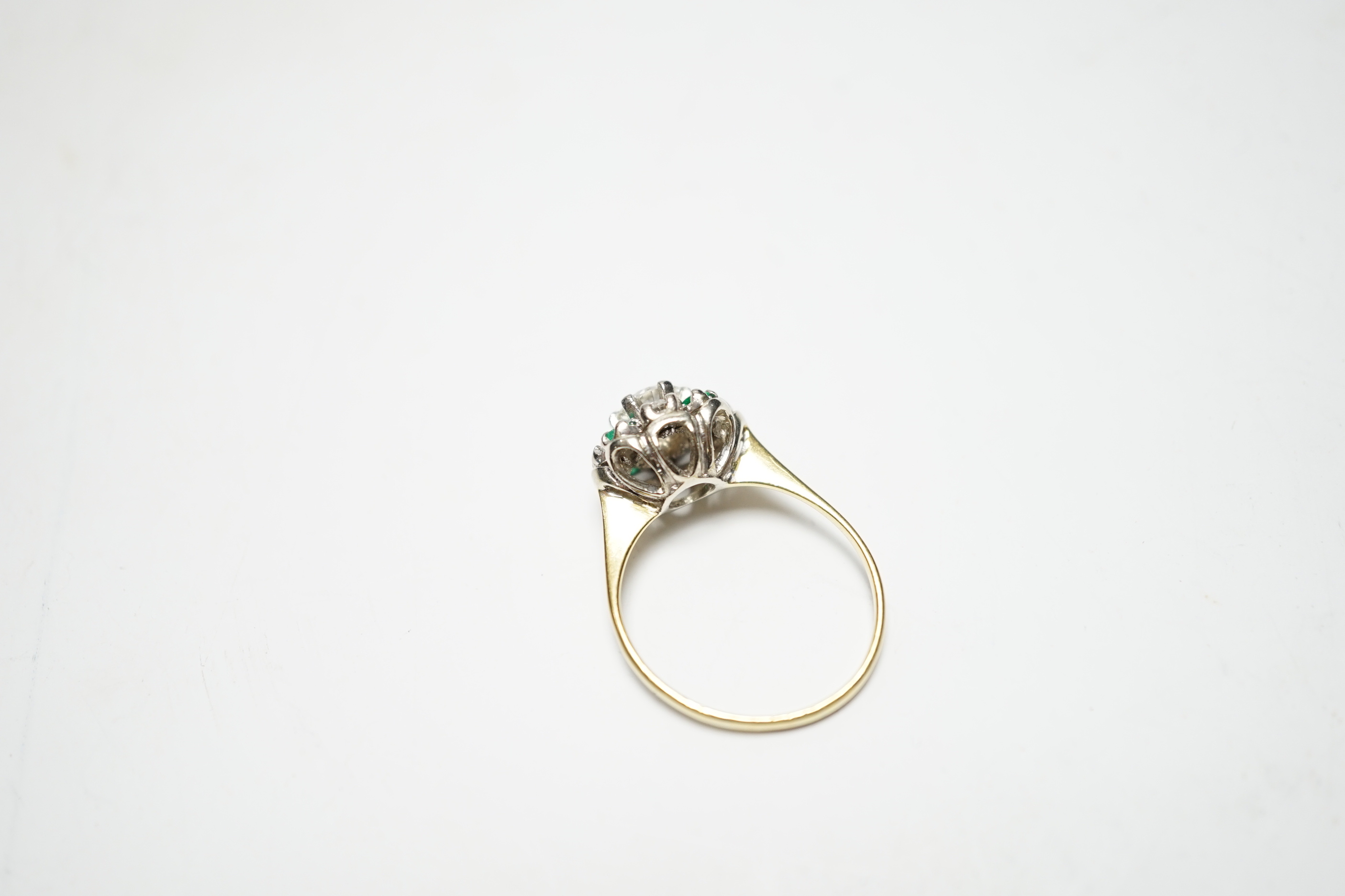 A yellow metal, diamond and emerald set flower head cluster ring, size P, gross weight 4 grams, the central diamond measuring approximately 5.5mm in diameter.